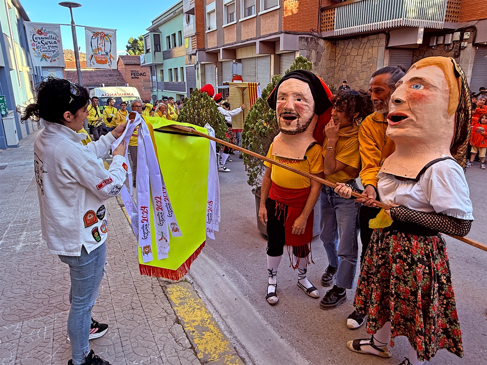 La regidora de Festes, Alba Martínez, lliura la cinta commemorativa a la colla Juvenil del Foment Cultural en l'acte d'inici de les Caramelles de Súria, al davant de la Casa de la Vila.