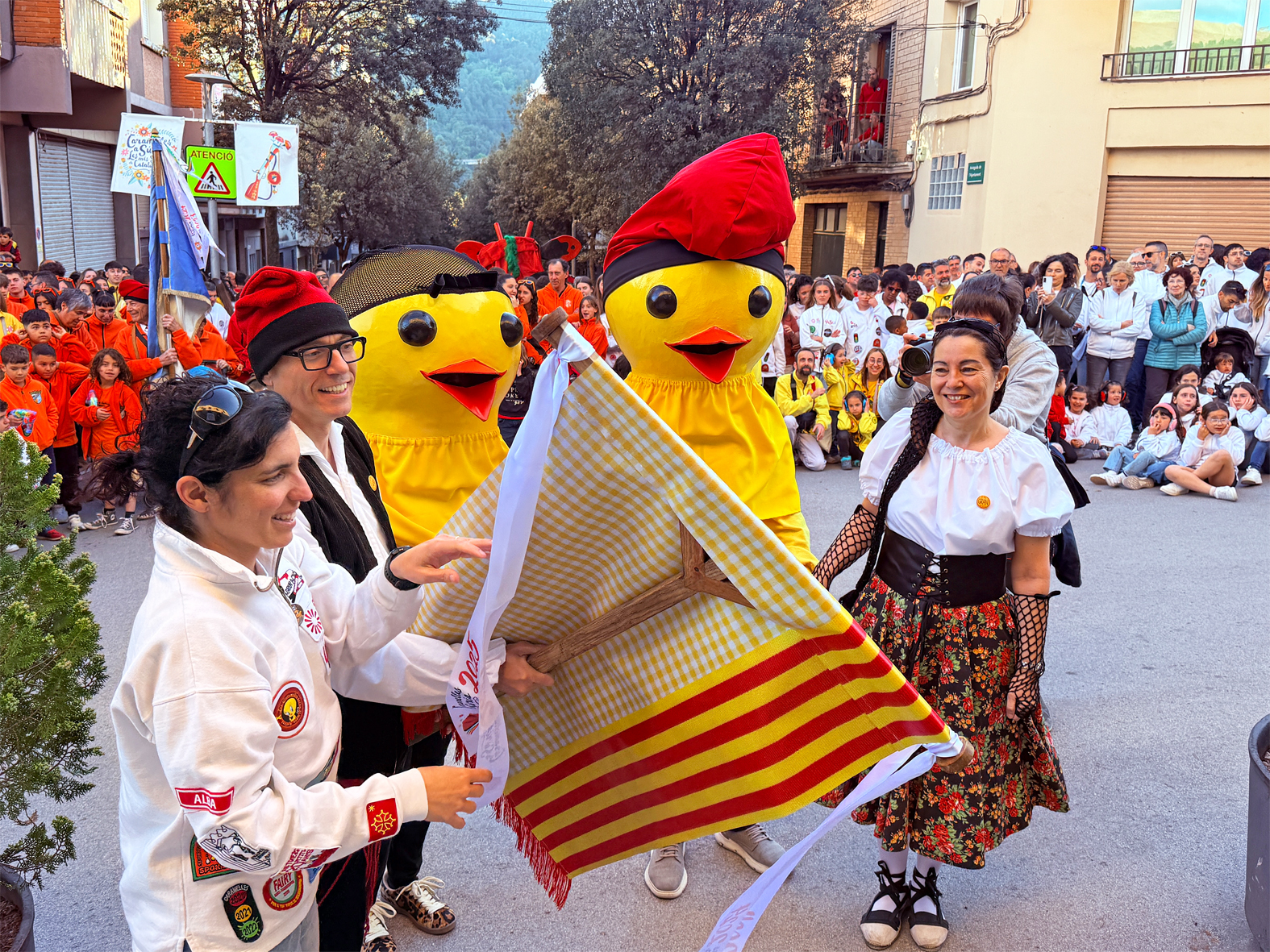 La regidora de Festes, Alba Martínez, lliura la cinta commemorativa a la colla Gran del Foment Cultural en l'acte d'inici de les Caramelles de Súria, al davant de la Casa de la Vila.