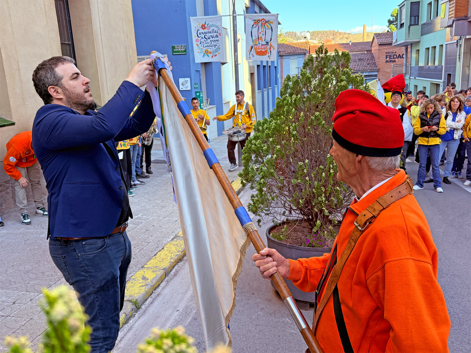 L'alcalde Albert Coberó lliura la cinta commemorativa a la colla del Tro Gros en l'acte d'inici de les Caramelles de Súria, al davant de la Casa de la Vila.