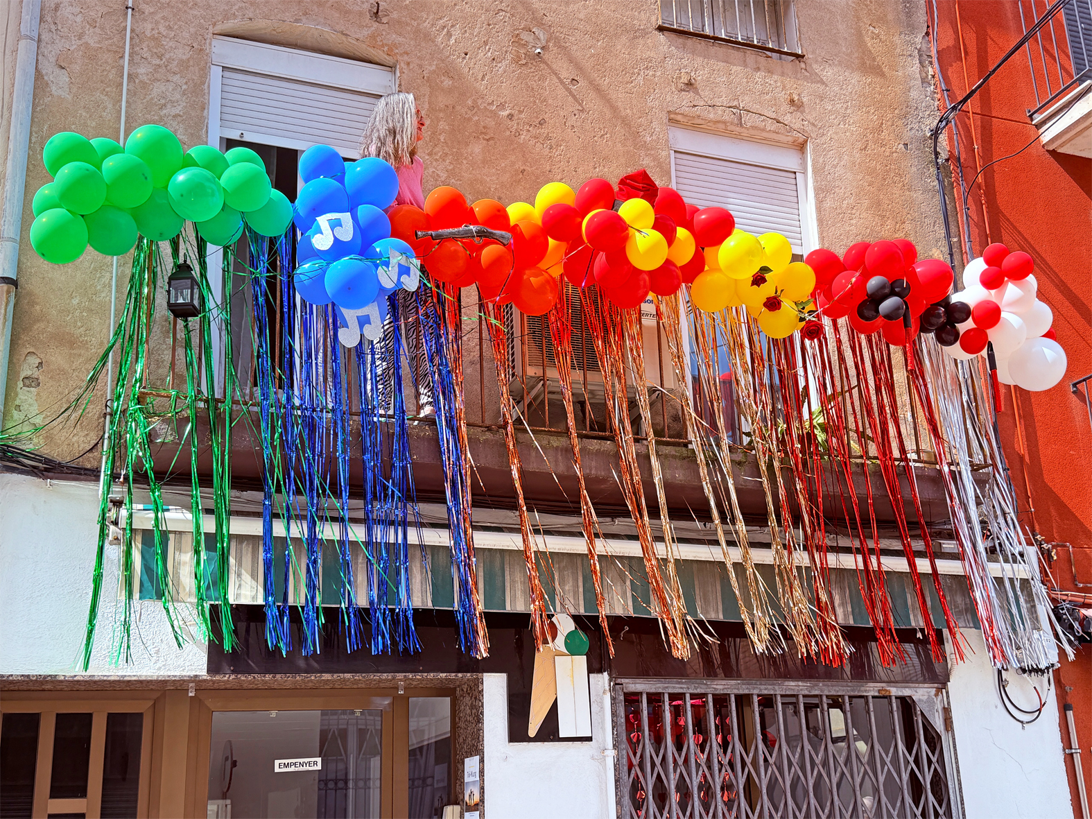 Guarniment d'un balcó del centre urbà amb els colors i elements identificatius de les colles de les Caramelles de Súria 2025.