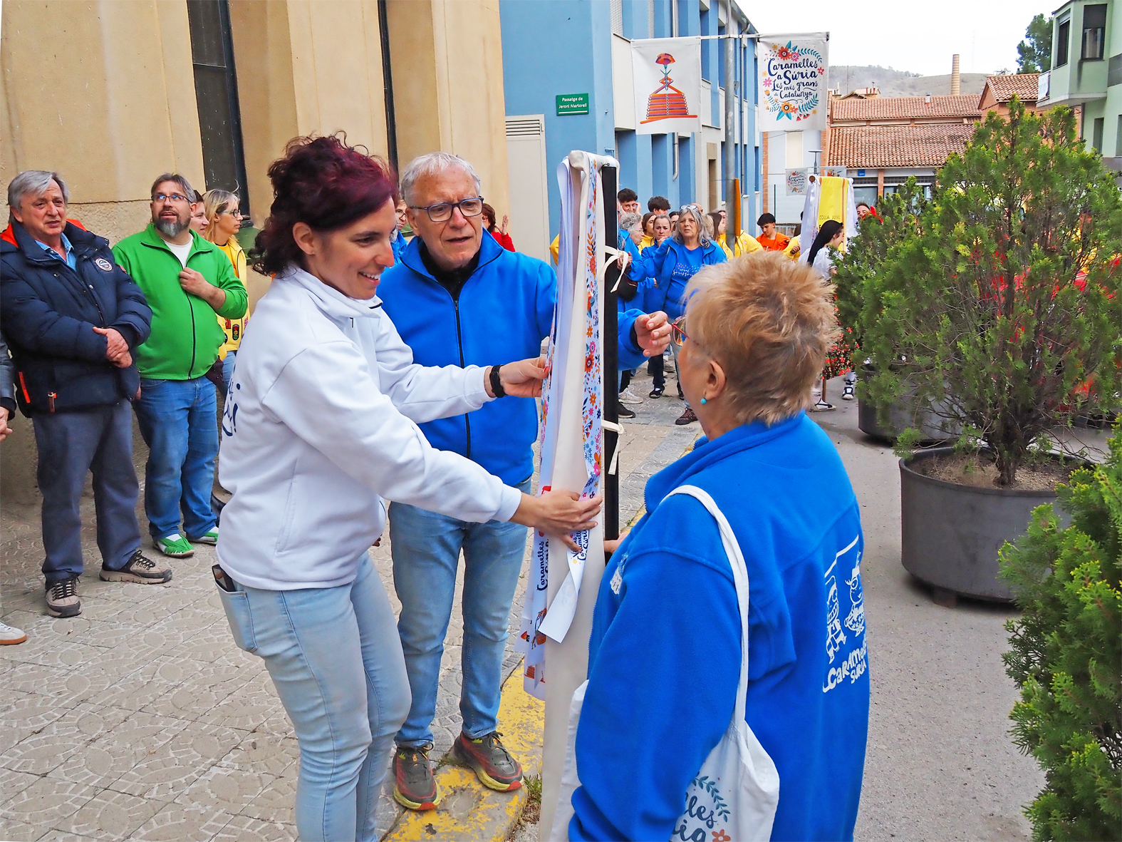 La regidora de Festes, Alba Mart&iacute;nez lliura la cinta commemorativa a la colla de la Coral S&ograve;rissons en l'acte d'inici de les Caramelles de S&uacute;ria, al davant de la Casa de la Vila.