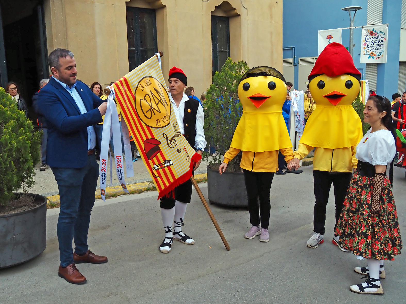 L'alcalde Albert Cober&oacute; lliura la cinta commemorativa a la colla Gran del Foment Cultural en l'acte d'inici de les Caramelles de S&uacute;ria, al davant de la Casa de la Vila.