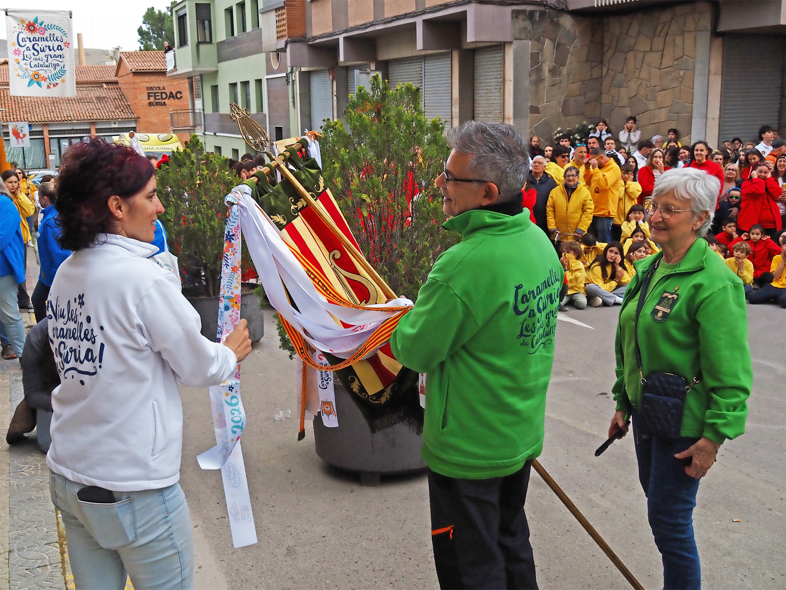 La regidora de Festes, Alba Mart&iacute;nez lliura la cinta commemorativa a la colla de La Llanterna en l'acte d'inici de les Caramelles de S&uacute;ria, al davant de la Casa de la Vila.