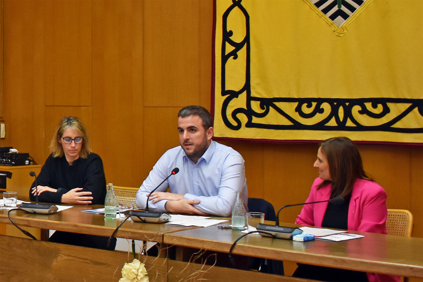 L'alcalde Albert Coberó parla durant l'acte del pregó de la Festa de Sant Sebastià, al costat de la directora general de Serveis Socials de la Generalitat, la surienca Mariona Homs, i la regidora de Festes, Alba Santamaria.